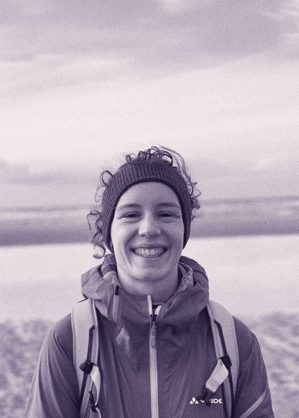 Medium close-up shot of a woman in her late twenties with curly hair and a headband, looking into the lens and smiling