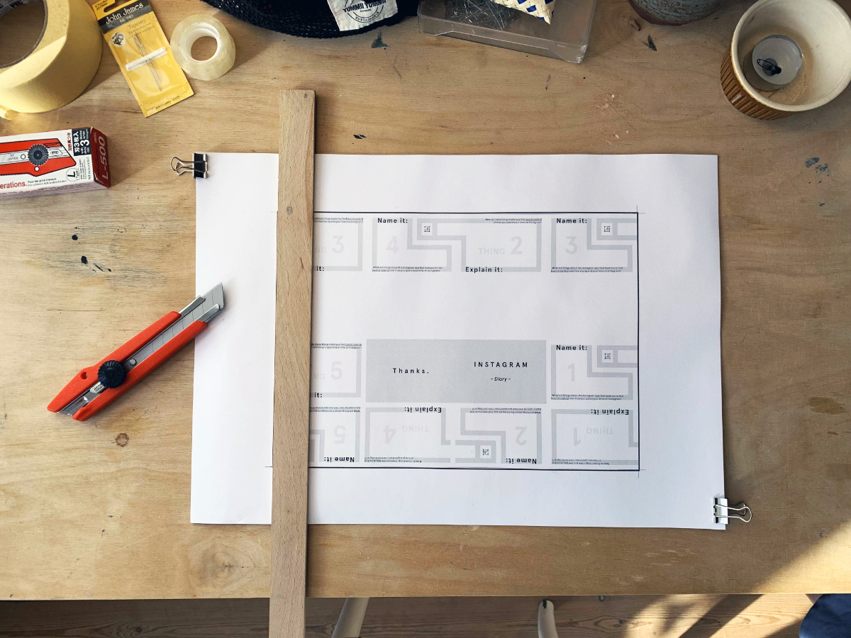 A wooden table seen from bird&#039;s eye view with a cutter knife, a ruler and a printed sheet of paper lying on it
